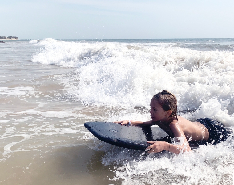 Ett barn på en surfbräda och en våg.