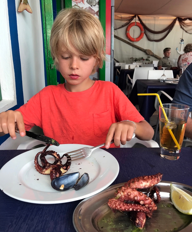 Ett barn äter bläckfisk.